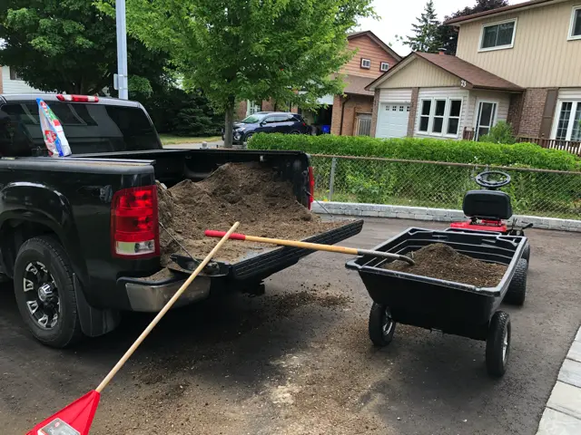 unloading 1 yard of soil with a riding mower and dump cart to cross seed and top dress a crappy backyard lawn