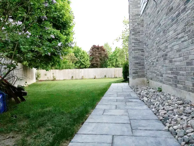 stone path connecting patio and driveway backfilled with medium sized river rock
