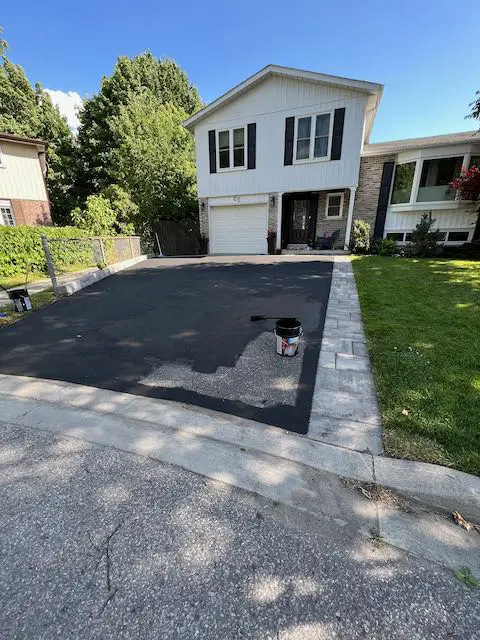 in progress applying driveway asphalt sealer